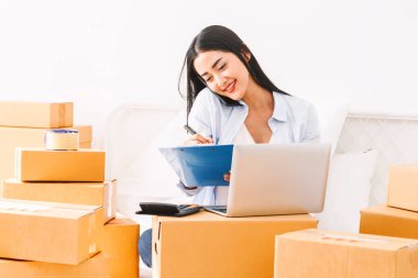 Genç kadın bağımsız çalışma ve denetim listesi ve karton siparişle yazma yatağa evde - KOBİ iş online ve teslimat kavramı kutu