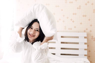 Kameraya gülümseyen ve onun odasına evde yatakta yastık ile rahatlatıcı güzel kadın