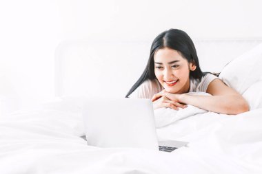 Rahatlatıcı ve sosyal uygulamalar kontrol ve smartphone ile çalışan home.woman, yatağa dijital dizüstü bilgisayar kullanan mutlu kadın