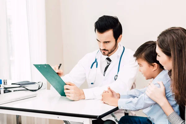 Doctor check up information with little boy and mom on doctors table in hospital.healthcare and medicine