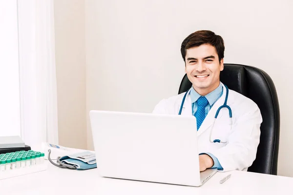 Medico Sorridente Guardando Fotocamera Con Stetoscopio Lavorare Sul Computer Portatile — Foto Stock