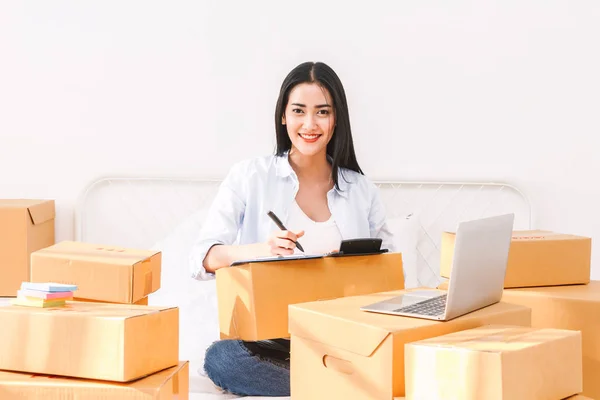 Junge Freiberufliche Mitarbeiterin Arbeitet Und Checkliste Und Schreibauftrag Mit Pappschachtel — Stockfoto