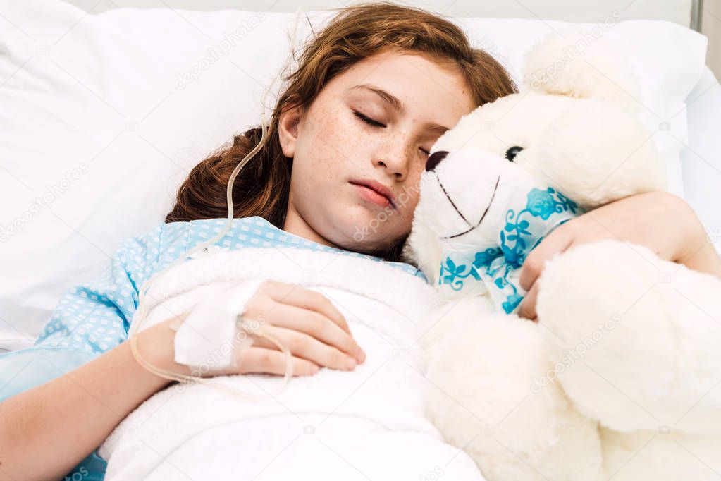 Sick little girl sleeping on the bed with medication through intravenous  in hospital