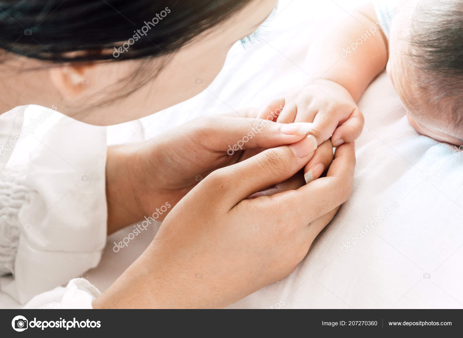 mother holding sleeping baby hand white bed love family concept