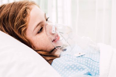 Cute little girl oxygen mask on her face on bed in the hospital