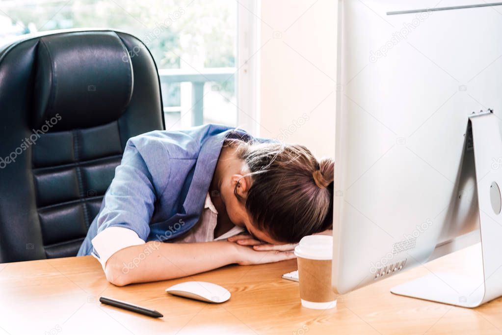 Tired overworked businesswoman sleeping on the table with laptop and documents at office