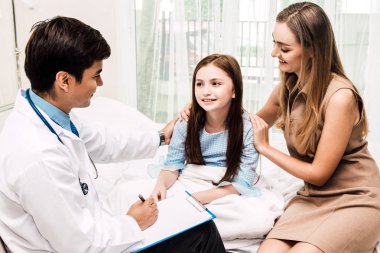 Danışmanlık doktor ve küçük kız ve annesi hastanede bilgilerini kontrol edin. Küçük bir kız sick.healthcare ve tıp vardır