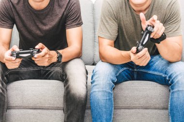 Kanepede oturan ve zevk iki arkadaş birlikte evde video oyunu oynamak