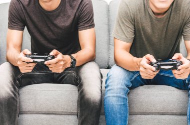 Kanepede oturan ve zevk iki arkadaş birlikte evde video oyunu oynamak