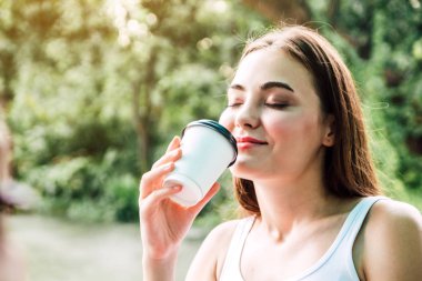 Genç kadın sakin ve doğal sabah taze hava arka plan üzerinde kahve içme zevk