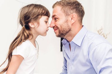 Küçük kız gülümseyerek ve burun birlikte evde dokunmadan baba ile. Gün kavramı, Aile ve baba sevgisi