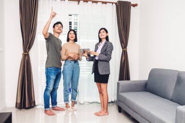 Emlakçı tutan tablet ve Genç çift Satılık bir ev ile konuş. iş ve ev kavramı