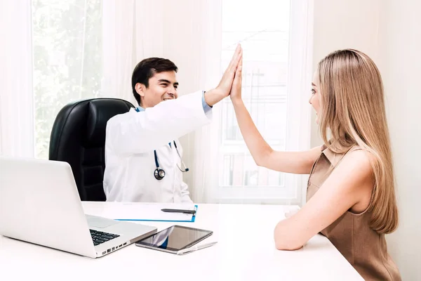 Doctor consulting and giving hi five with woman patient on doctors table in hospital.healthcare and medicine