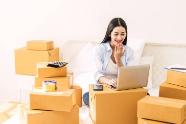 Genç kadın bağımsız çalışma ve kullanım dizüstü bilgisayar ile karton kutu yatağa evde - KOBİ iş online ve teslimat kavramı