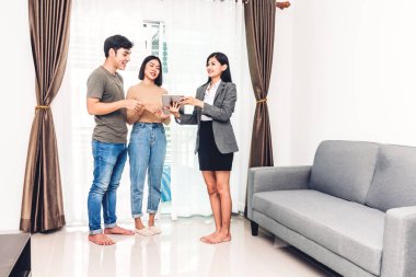 Emlakçı tutan tablet ve Genç çift Satılık bir ev ile konuş. iş ve ev kavramı