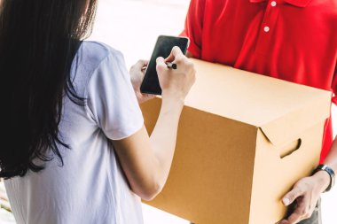 Kırmızı uniform.courier hizmet anlayışı içinde teslim adamla smartphone alıcı paket için karton kutu ile imza koyarak kadın