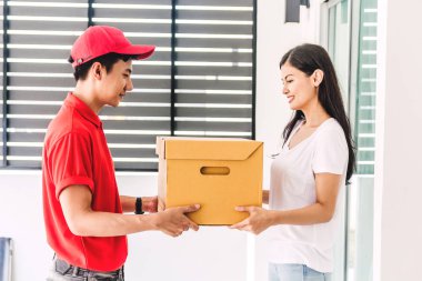 Kırmızı üniformalı teslimatçıdan gelen teslimat kutusunu kabul eden kadın. Kurye hizmeti kavramı.