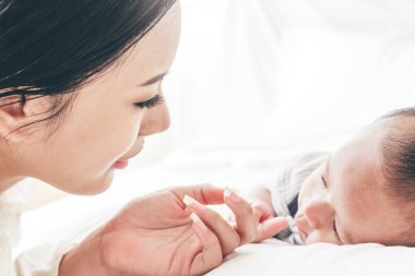 Bebek el Beyaz yatakta uyuyan anne holding. Aşk aile kavramının