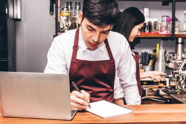 Gülümseyen ve dizüstü bir kafede sayaç barın arkasında çalışan çift küçük işletme sahibi portresi. Çift barista kahve makinesi kahve café'de yapmak için kullanma