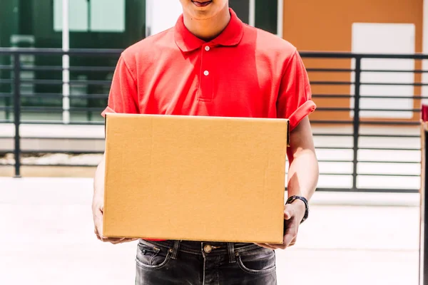 Kırmızı Üniformalı Mutlu Teslimatçı Elinde Karton Kutuyla Müşteri Evinin Yanında — Stok fotoğraf