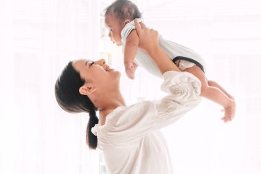 Yatak odası evde bebekle oynarken mutlu gülümseyen anne portresi. Aşk aile kavramının