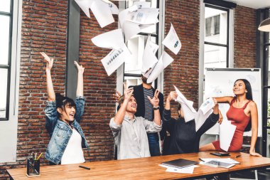 Başarılı bir grup gündelik iş gevşetici ve modern çalışma tavan arasına kağıt fırlatıcı. Yaratıcı iş adamları bunu kollarını kaldırarak kutluyor. Takım çalışması ve başarı kavramı.