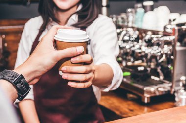 Kadın barista sayaç bar ve kafe müşteriye veren kahve fincanı arkasında