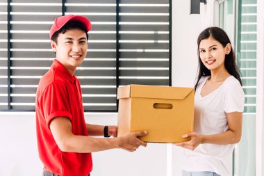 Kırmızı üniformalı teslimatçıdan gelen teslimat kutusunu kabul eden kadın. Kurye hizmeti kavramı.