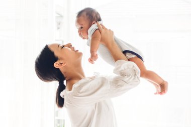 Yatak odası evde bebekle oynarken mutlu gülümseyen anne portresi. Aşk aile kavramının