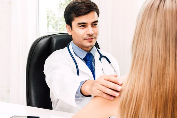 Doctor consulting and holding hand female patient reassuring with care on doctors table in hospital.healthcare and medicine