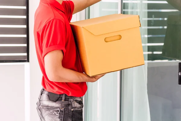 Happy Delivery Man Red Uniform Holding Χαρτόνι Κουτί Στέκεται Κοντά — Φωτογραφία Αρχείου