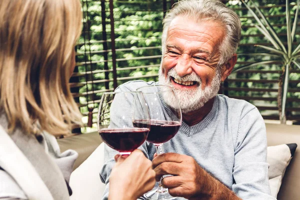 Senior couple relax talking and drinking wine glasses together on sofa in living room at home.Retirement couple concept