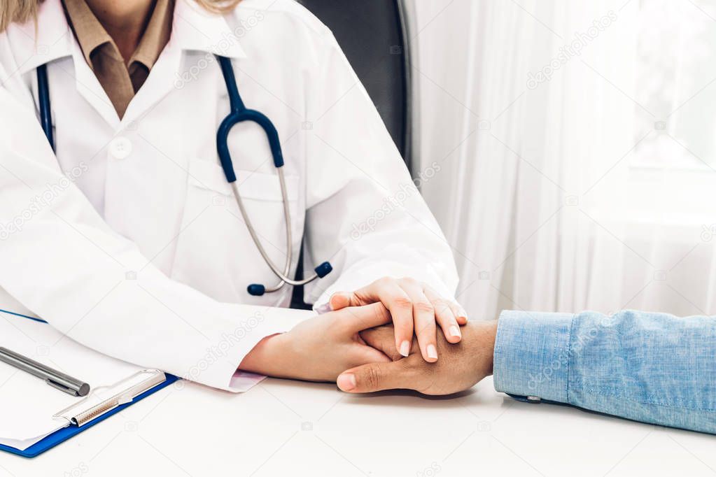 Female doctor consulting and holding hand male patient reassuring with care on doctors table in hospital.healthcare and medicine