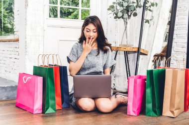 Güzel kadın shoping online dizüstü bilgisayar ve renkli alışveriş çantası yere evde oturmak teknoloji ile