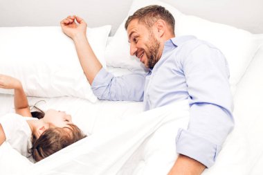 Babası ile eğleniyor ve evde yatakta birlikte oynayan küçük kızı. Gün kavramı, Aile ve baba sevgisi