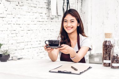 Gülümseyen ve kahve bir kafede sayaç barın arkasında tutarak kadın barista küçük işletme sahibi portresi