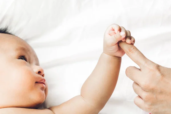 婴儿手拿着母亲的手指在白色的床上 爱的家庭和婴儿保护的概念 — 图库照片