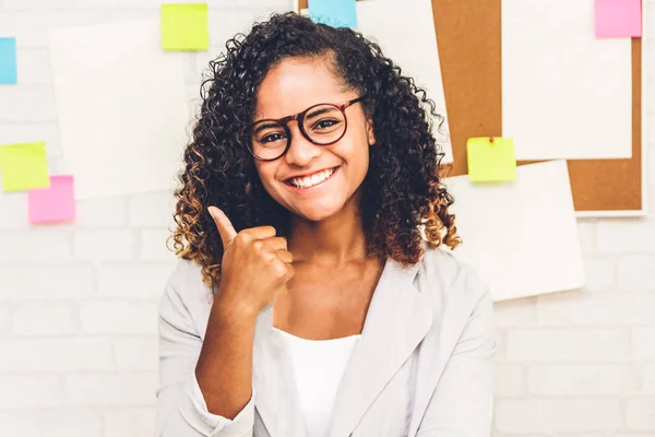 Beautiful professional business african american black woman with eyeglasses smiling at camera and showing thumbs up at office