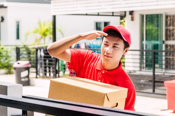 Felice Uomo Consegna Uniforme Rossa Contenente Scatola Cartone Piedi Vicino — Foto Stock