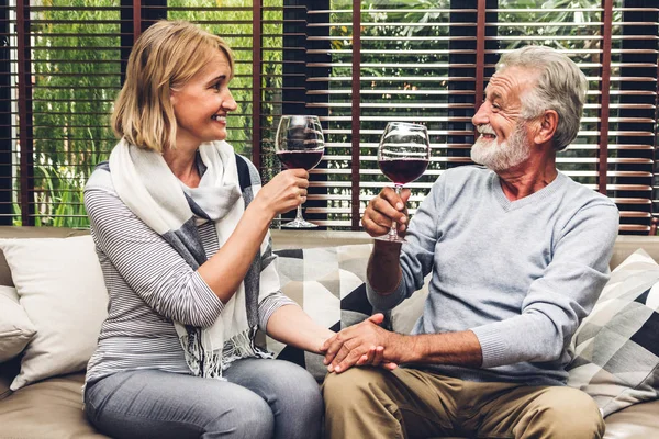 Senior couple relax talking and drinking wine glasses together on sofa in living room at home.Retirement couple concept