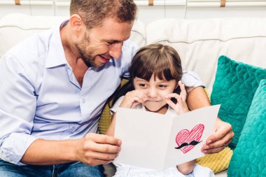 Babası ile eğleniyor ve evde kanepede birlikte kitap okumak küçük kızı. Küçük kız ve baba hikaye kitabı ile zevk. Aile sevgisi ve kavram