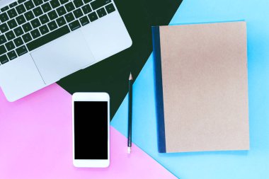 Mavi ve pembe pastel arka plan üzerinde üstten görünüm dizüstü bilgisayar ve mockup Smartphone ile boş perde. Düz yatıyordu