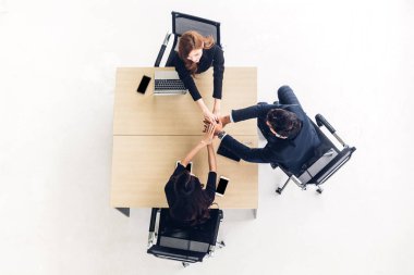 Üstten görünüm başarılı grup iş insan yığını ve ellerini birlikte ofis ahşap masa üzerine koyarak. Dostluk ekip çalışması kavramı