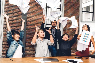 Başarılı bir grup gündelik iş gevşetici ve modern çalışma tavan arasına kağıt fırlatıcı. Yaratıcı iş adamları bunu kollarını kaldırarak kutluyor. Takım çalışması ve başarı kavramı.