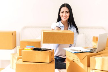 Genç kadın bağımsız çalışma ve kullanım dizüstü bilgisayar ile karton kutu yatağa evde - KOBİ iş online ve teslimat kavramı