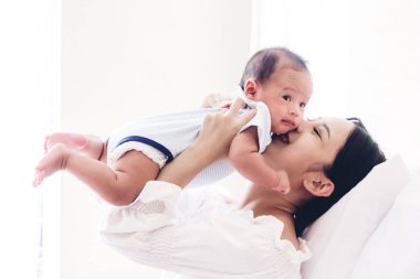 Yatak odası evde bebekle oynarken mutlu gülümseyen anne portresi. Aşk aile kavramının