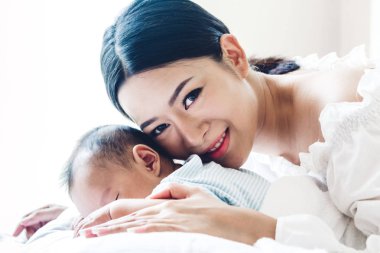 Yatağa evde bebekle oynarken mutlu gülümseyen anne portresi. Aşk aile kavramının