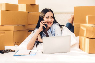 Genç kadın bağımsız çalışma ve kullanım dizüstü bilgisayar ile karton kutu yatağa evde - KOBİ iş online ve teslimat kavramı