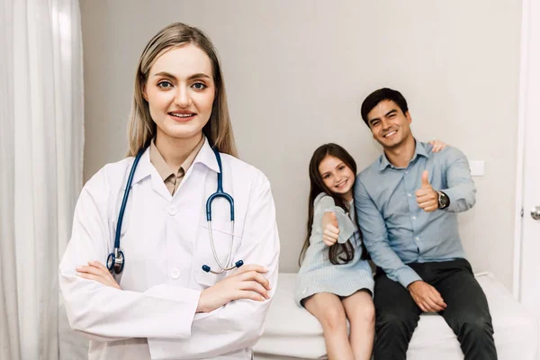 Médico Olhando Para Câmera Enquanto Jovem Família Pai Menina Fundo — Fotografia de Stock