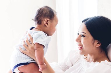 Yatağa evde bebekle oynarken mutlu gülümseyen anne portresi. Aşk aile kavramının